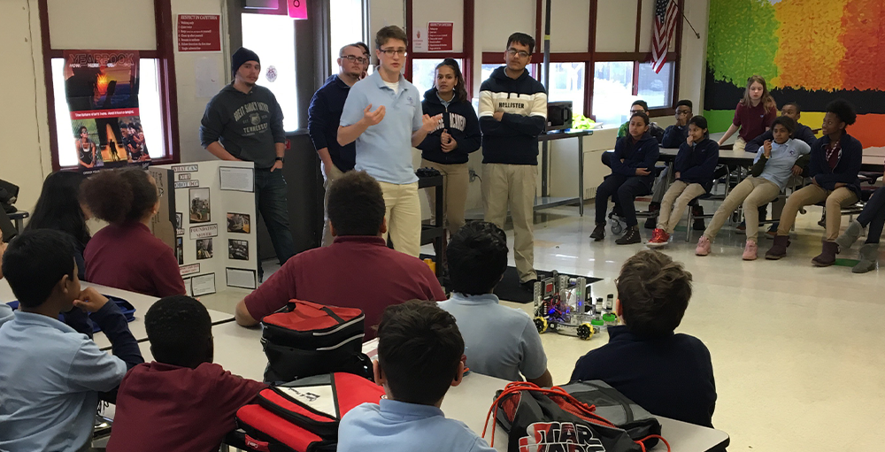High school robotics team visit the middle school and share with them information about the robotics program